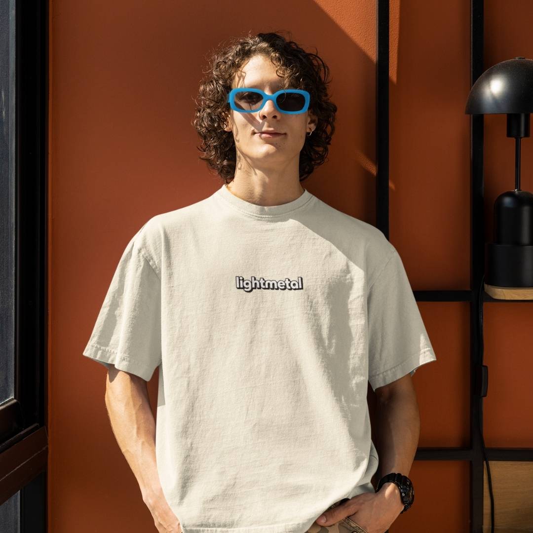 Corporate Beige - Person wearing a light-colored t-shirt with 'lightmetal' text, standing against an orange wall.