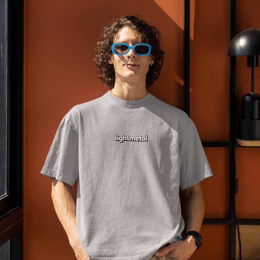 Stealth Gray - Person wearing a gray 'lightmetal' t-shirt with blue sunglasses against an orange wall.