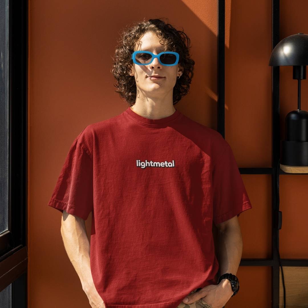 Primal Red - Person wearing a red 'lightmetal' t-shirt with blue sunglasses indoors.