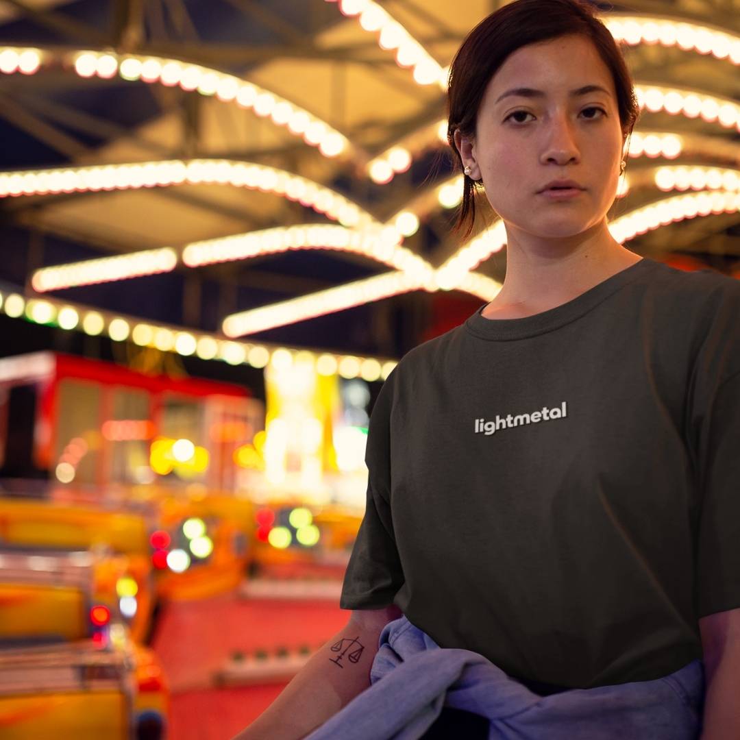 Honest Black - Person wearing a 'lightmetal' t-shirt in a colorful, blurred indoor setting
