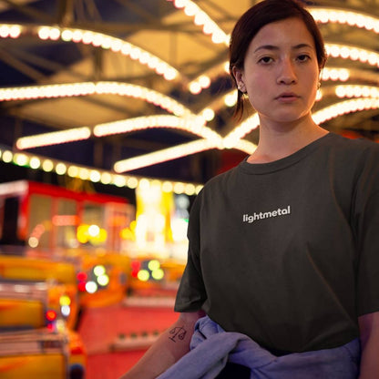 Honest Black - Person wearing a 'lightmetal' t-shirt in a colorful, blurred indoor setting