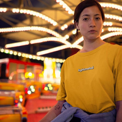 Wild Yellow - Person wearing a yellow 'lightmetal' t-shirt in a colorful, possibly amusement park setting.