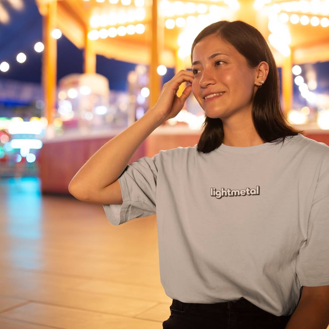 Stealth Gray - Woman wearing a 'lightmetal' t-shirt in front of a blurred amusement park background