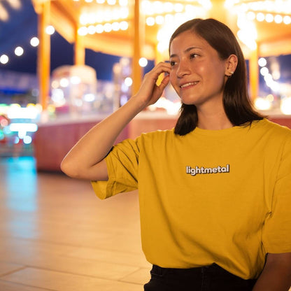 Wild Yellow - Woman wearing a yellow 'lightmetal' shirt in an outdoor setting with blurred lights in the background