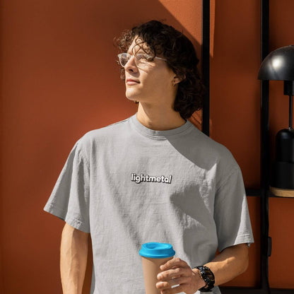 Stealth Gray - Person wearing a gray 'lightmetal' t-shirt holding a coffee cup against an orange wall.